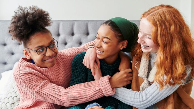 Three girls smiling together to illustrate story promoting children and young people's engagement grants for community organisations